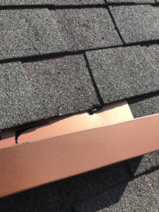 aluminum-flashing-sticking-out-from-under-a-roof-shingle